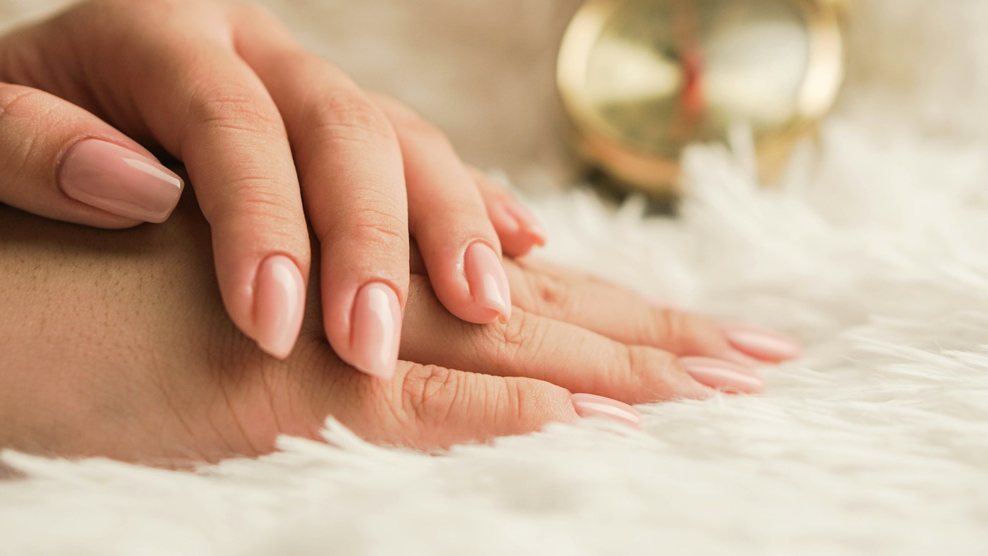 Primer plano de unas manos con una manicura rosa suave